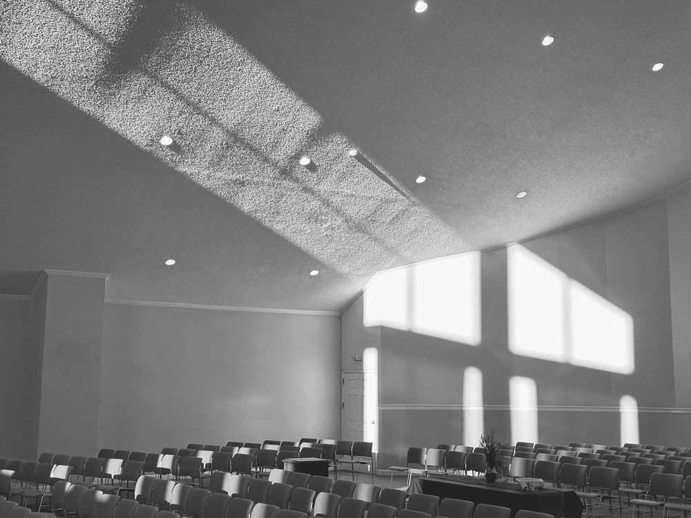 A black-and-white photo of the empty Trinity sanctuary, as shadows are cast on the curved wall.